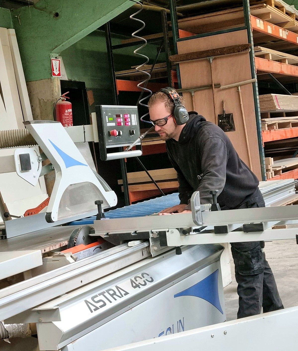 Een plaat wordt op maat gezaagd aan de formaatzaag in het atelier