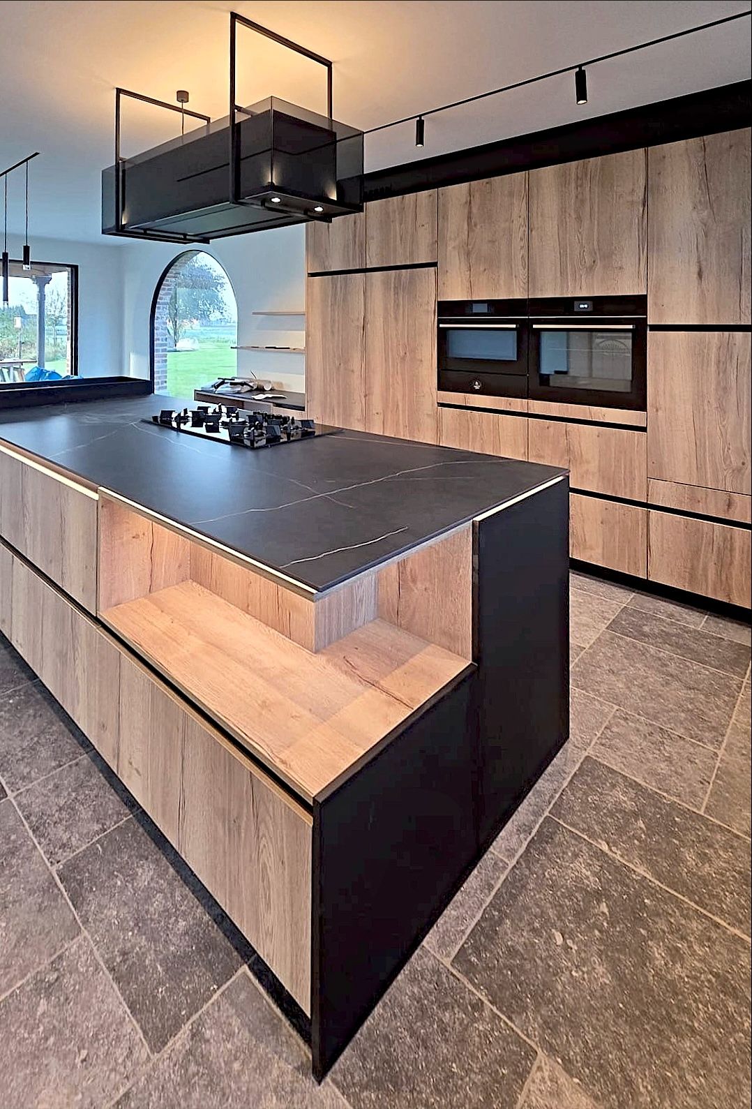 Een geplaatste keuken in eik en zwart met een lang eiland