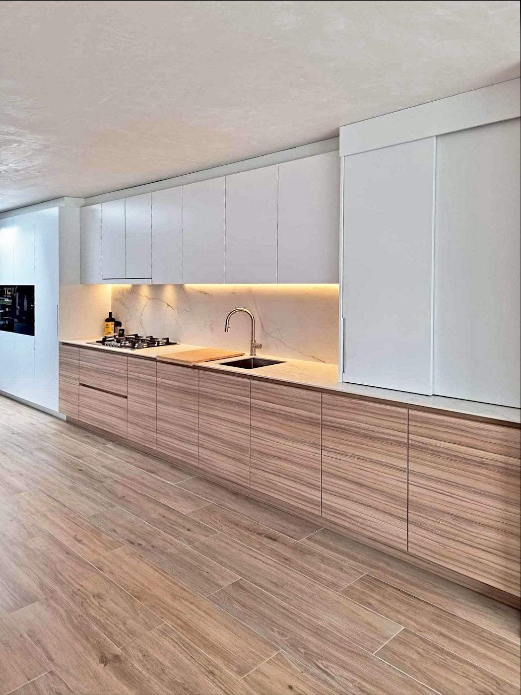 Lange keukenwand met houten onderkasten en witte bovenkasten